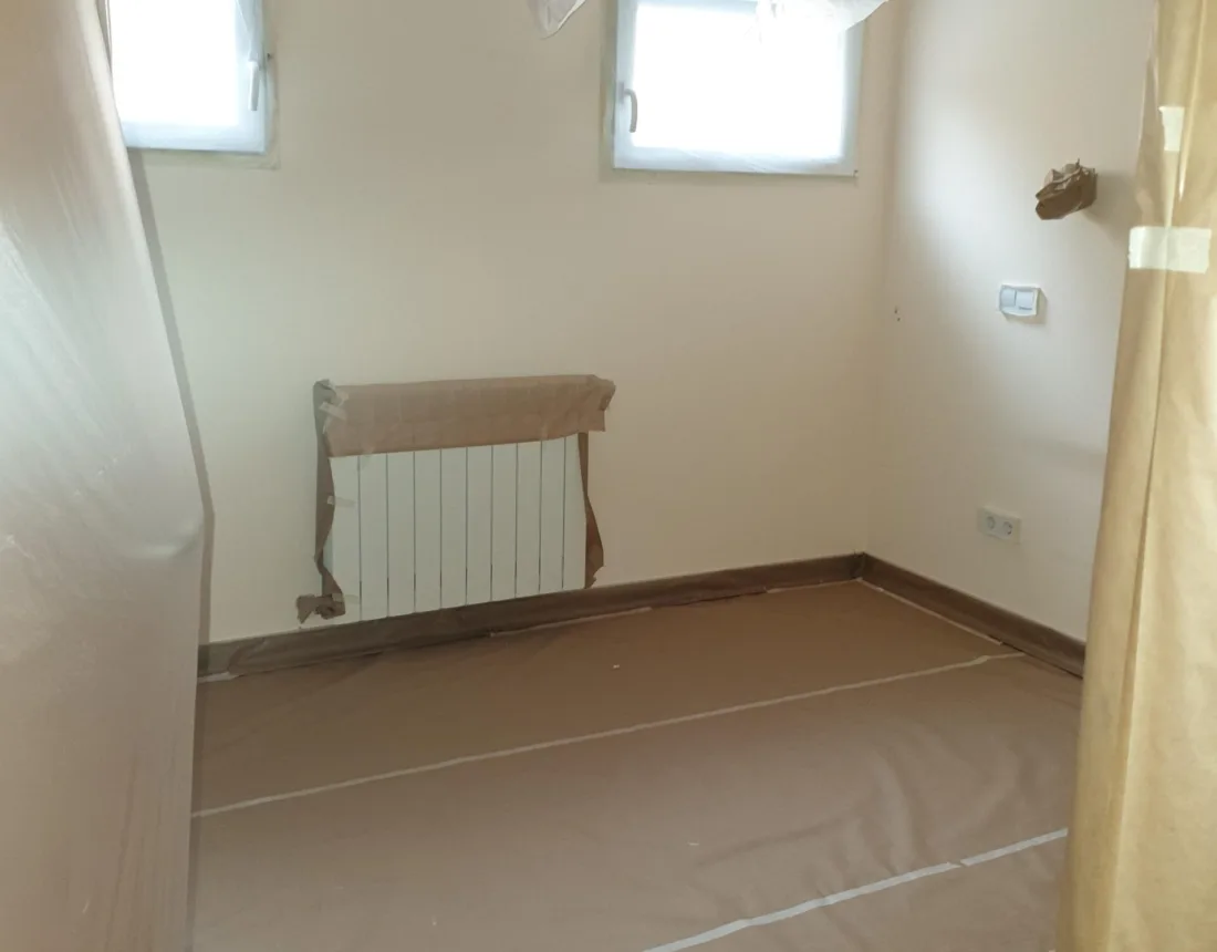 Dormitorio con el ventilador de techo embolsado y el radiador enmascarado