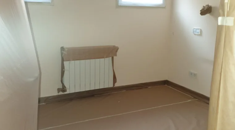 Dormitorio con el ventilador de techo embolsado y el radiador enmascarado