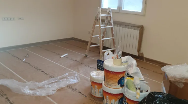 Salón amplio con el suelo empapelado, escalera y botes listos para empezar