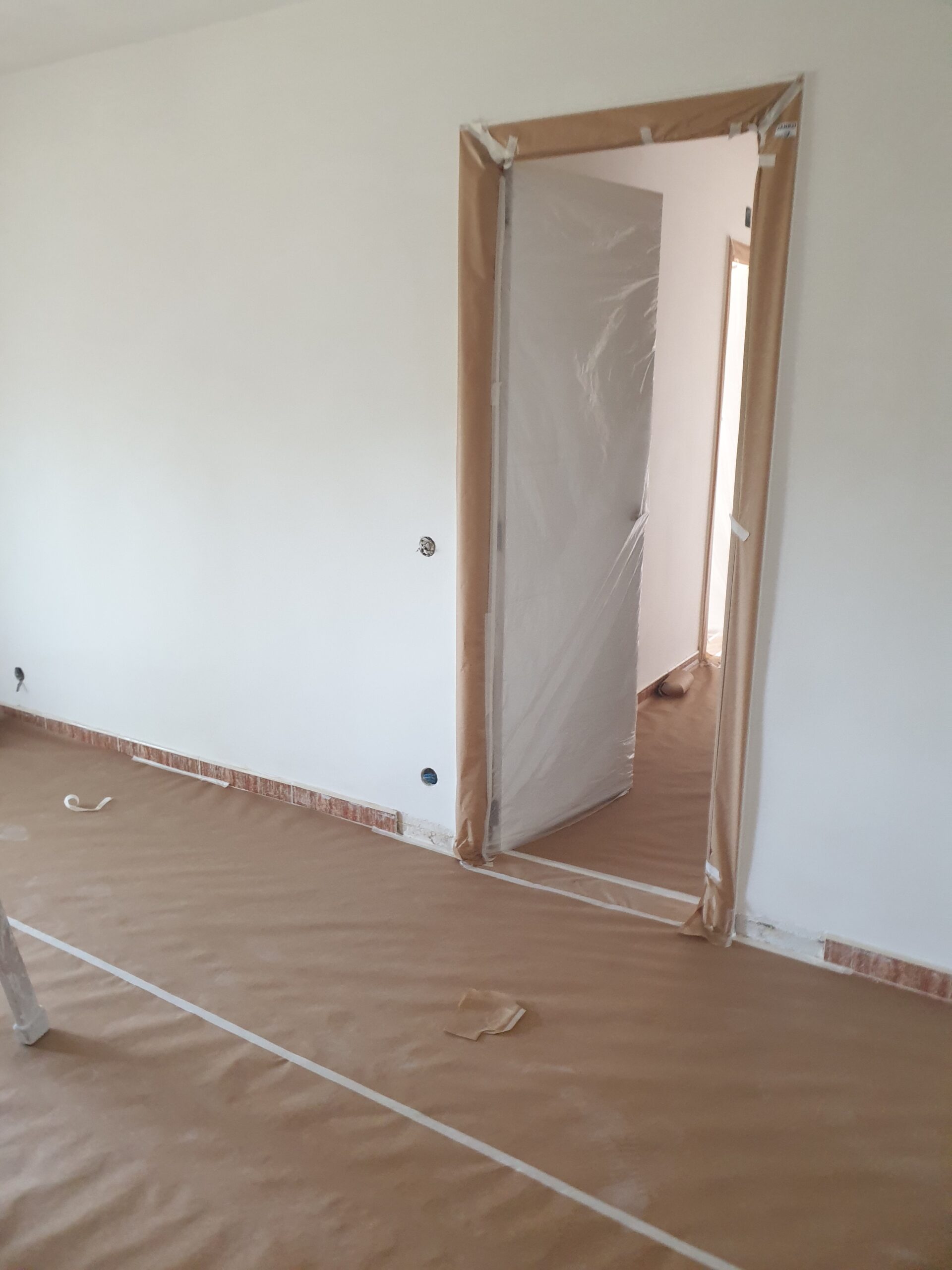 Puerta y cerco cubiertos con papel y plástico durante los trabajos de pintura, en una vivienda de Guadarrama
