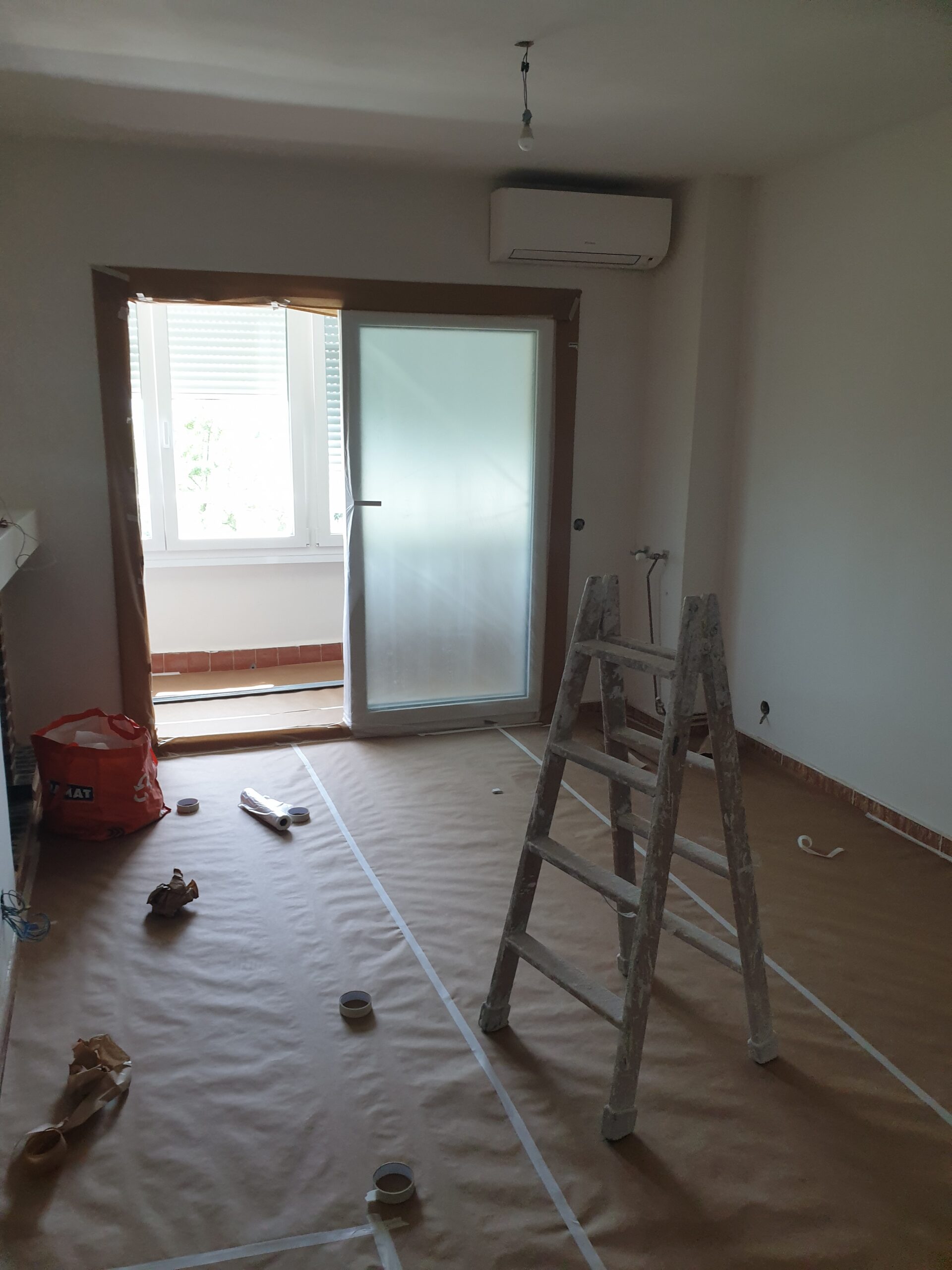 Salón de una vivienda de Guadarrama con el suelo empapelado y la balconera enmascarada antes de pintar