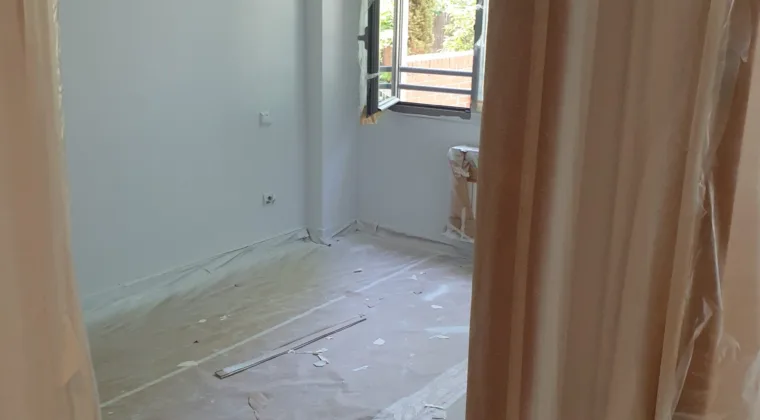 Dormitorio con la ventana y el suelo cubiertos antes de pintar