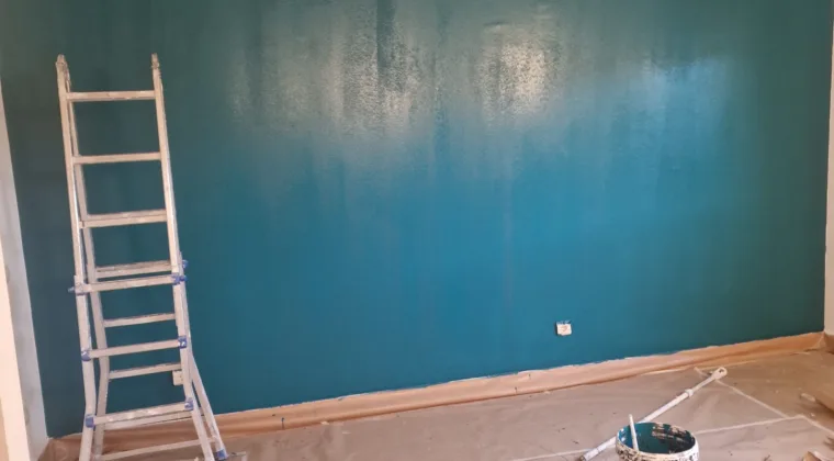 Pared pintada en verde azulado bajo techo de vigas de madera