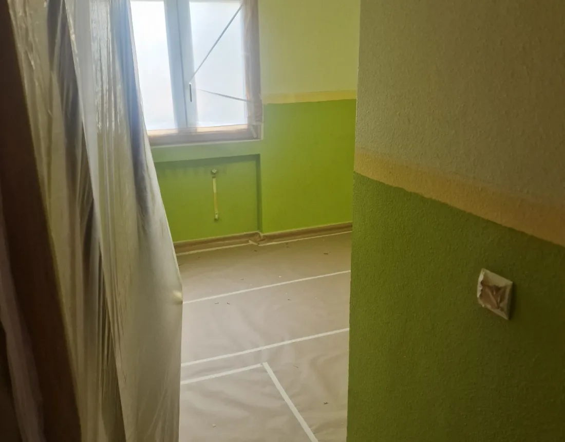 Pasillo con una pared pintada en verde pistacho y el suelo empapelado