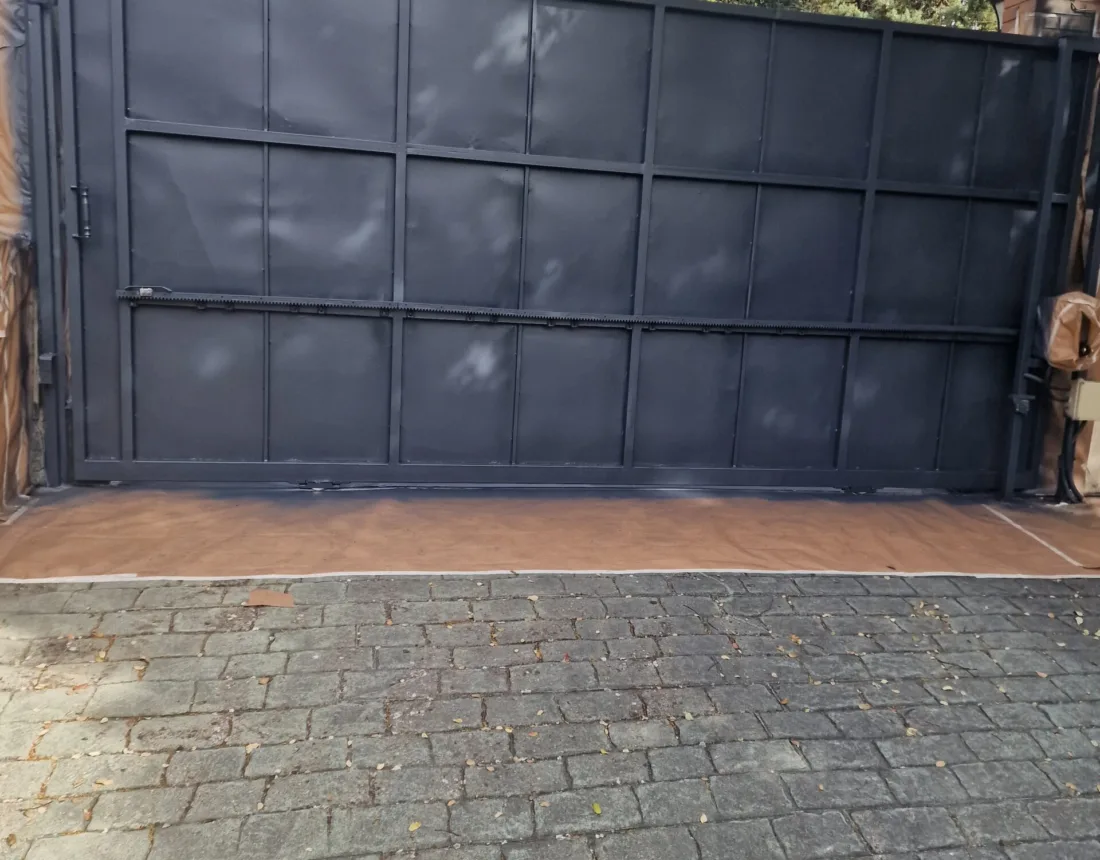 Puerta corredera metálica terminada en gris antracita sobre adoquín