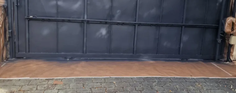 Puerta corredera metálica terminada en gris antracita sobre adoquín