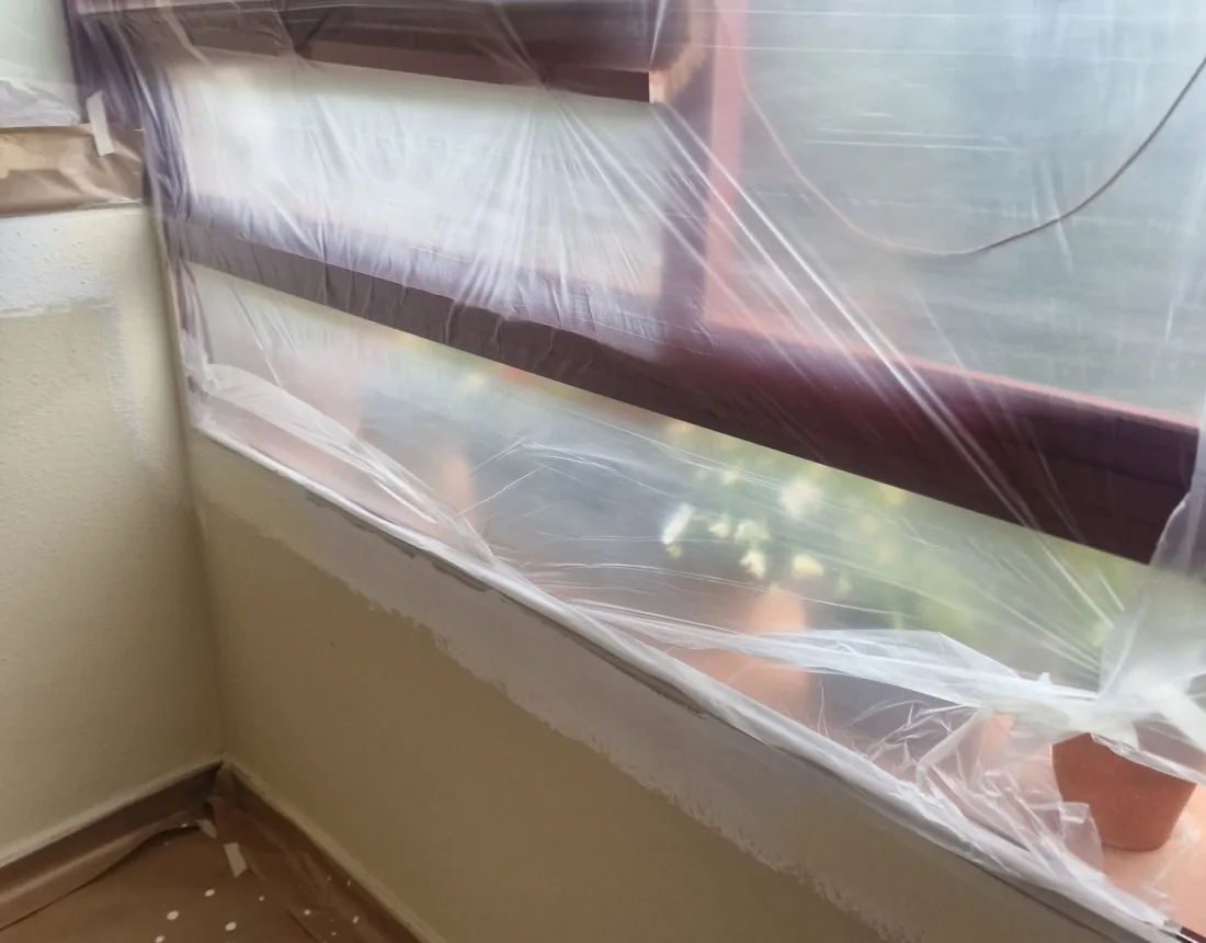 Ventanal y alféizar cubiertos con plástico durante los trabajos de pintura