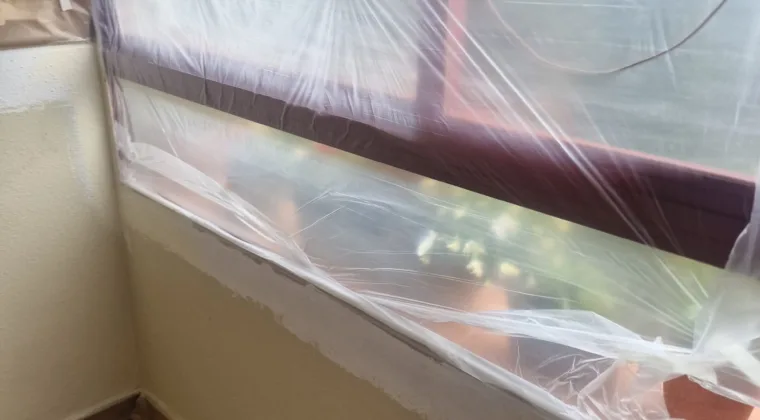 Ventanal y alféizar cubiertos con plástico durante los trabajos de pintura