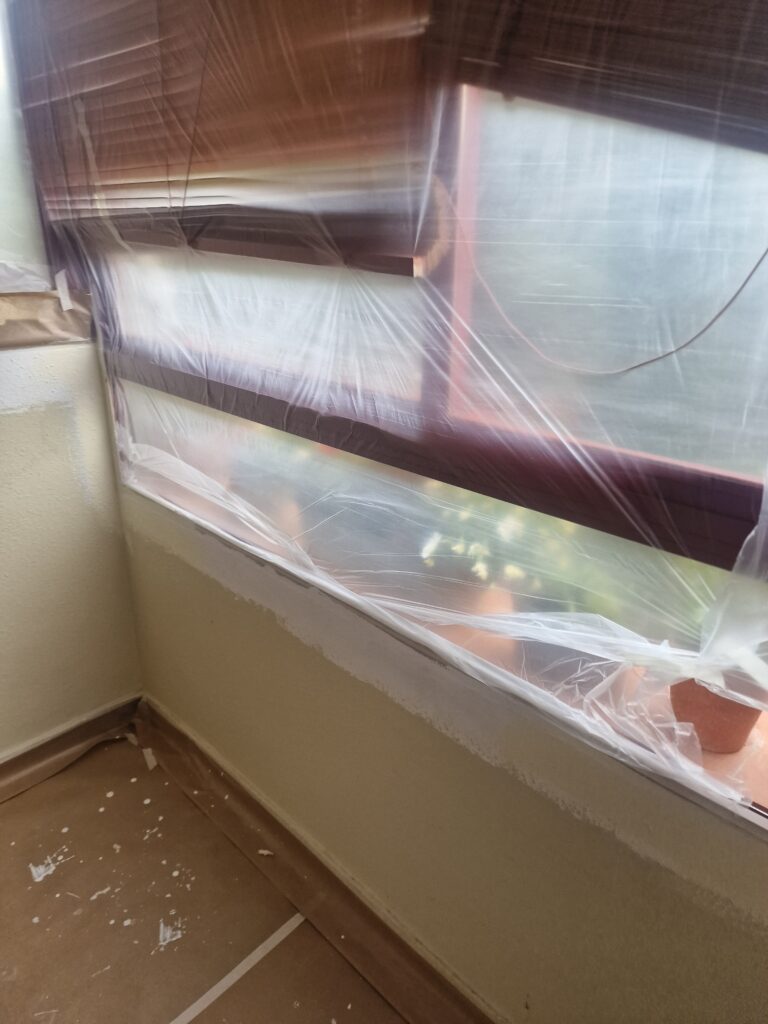 Ventanal y alféizar cubiertos con plástico durante los trabajos de pintura