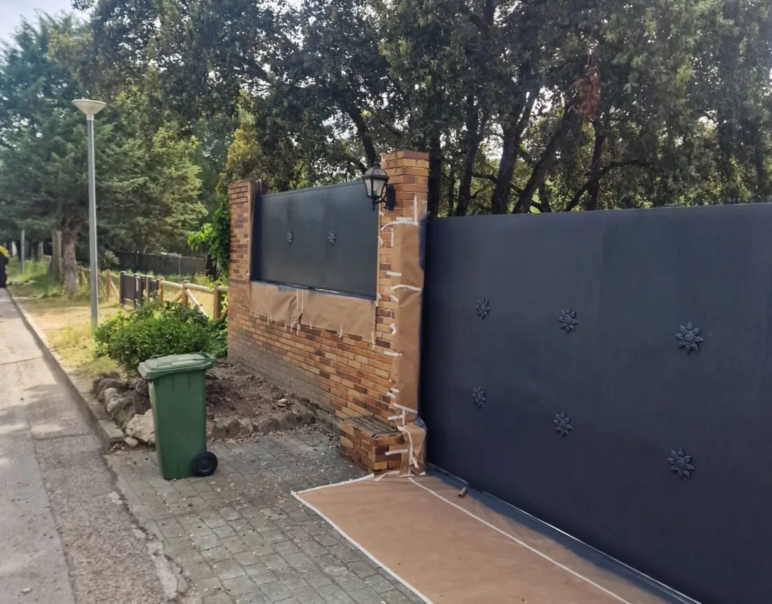 Verja corredera y muro de cerramiento pintados en gris antracita, vistos desde la calle