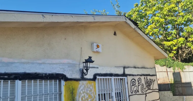 Fachada de un anexo de chalet en Majadahonda con pintadas de espray negro y amarillo antes de la limpieza