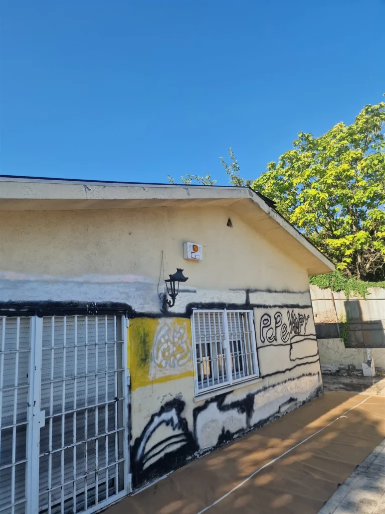 Fachada de un anexo de chalet en Majadahonda con pintadas de espray negro y amarillo antes de la limpieza