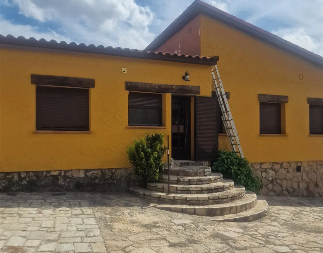 Fachada de chalet en Las Rozas terminada en amarillo mostaza sobre zócalo de piedra