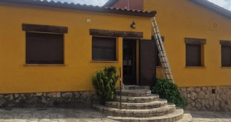 Fachada de chalet en Las Rozas terminada en amarillo mostaza sobre zócalo de piedra
