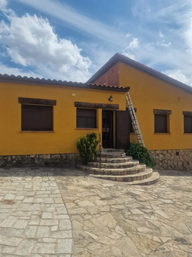 Fachada de chalet en Las Rozas terminada en amarillo mostaza sobre zócalo de piedra