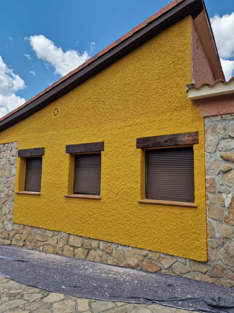 Fachada del chalet de Las Rozas durante la obra, con ventanas enmascaradas y zócalo de piedra protegido