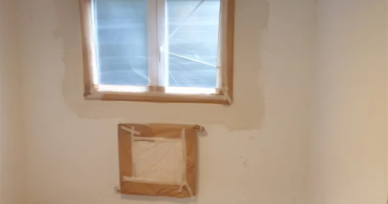 Dormitorio con ventana y radiador enmascarados y el suelo empapelado, en Colmenarejo