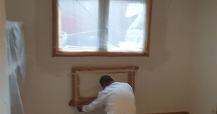 Pintor enmascarando el radiador y el cerco de la ventana en una vivienda de Colmenarejo