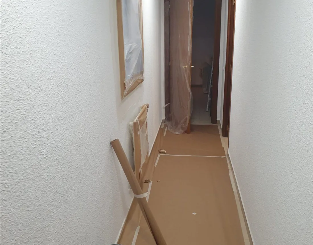 Pasillo con el suelo empapelado y los cercos enmascarados durante la obra, en Colmenarejo