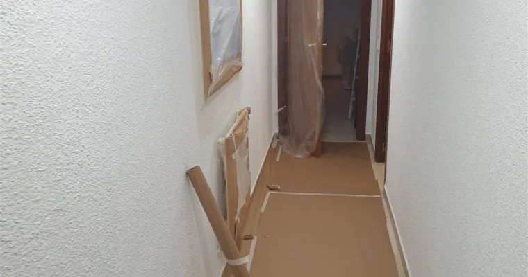 Pasillo con el suelo empapelado y los cercos enmascarados durante la obra, en Colmenarejo
