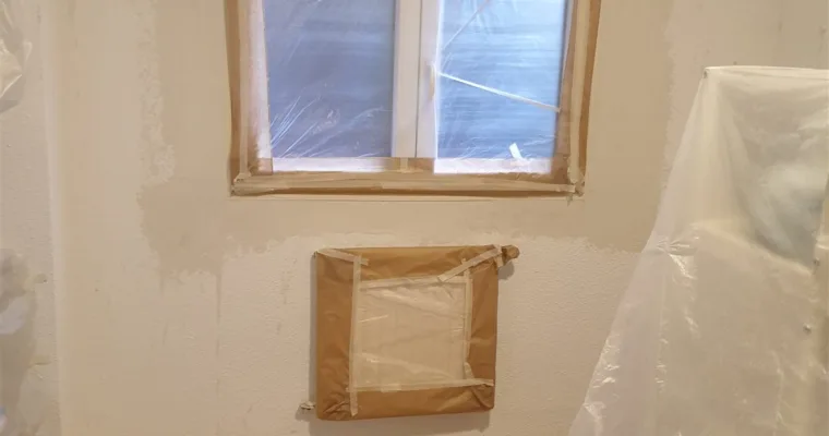 Ventana y radiador enmascarados antes de pintar, en una vivienda de Colmenarejo