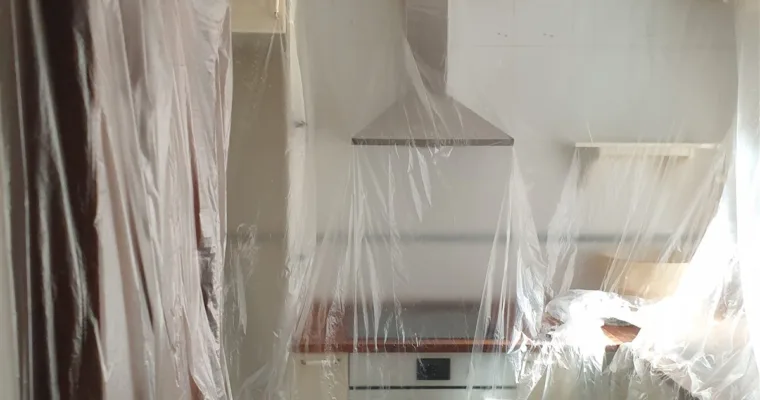 Cocina con la campana, los muebles y la encimera cubiertos con plástico antes de pintar, en Los Arroyos