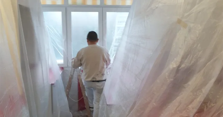 Pintor trabajando tras el plástico de protección en una vivienda de Los Arroyos