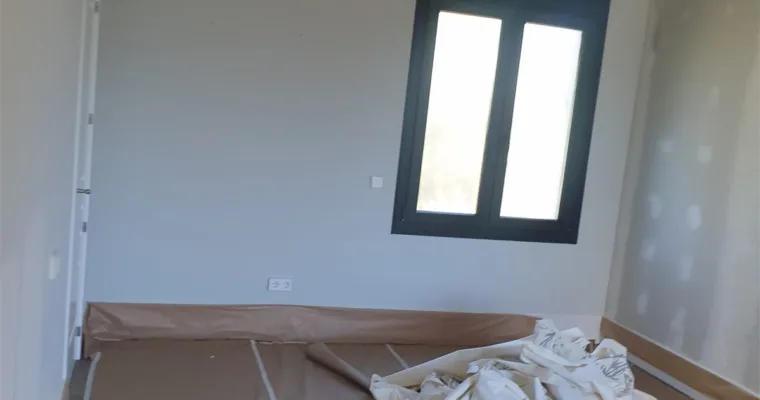 Estancia terminada con ventana de carpintería negra y suelo protegido, en un chalet de Torrelodones