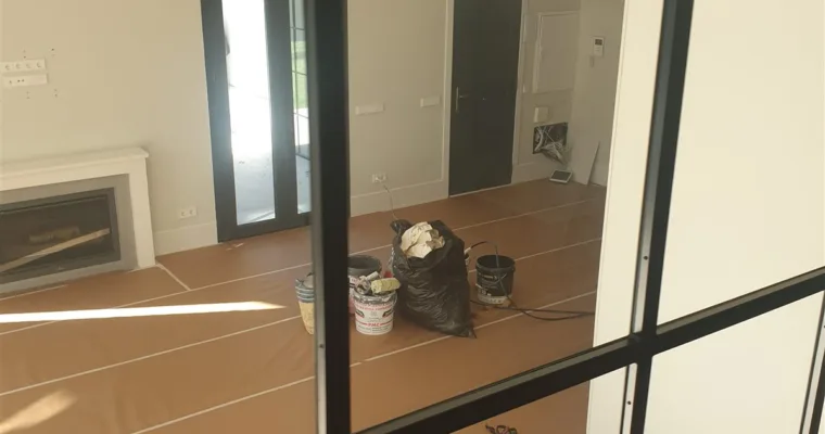 Salón a doble altura con carpintería de acero negro protegido durante la obra, en Torrelodones